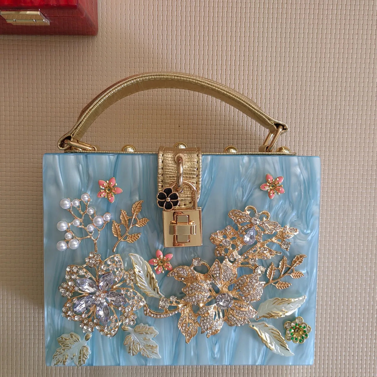 Bolsa Minaudière Metálica com Detalhes em Diamantes e Forro em Couro Sintético.